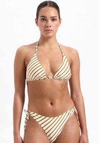 Set di bikini a righe in bianco e oro. Top con collo halter e coppe triangolari con hardware scorrevole. I calzoni presentano lacci laterali e motivo coordinato.