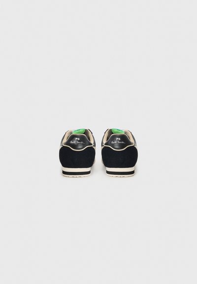 Suede shoes in navy with beige accents. Features black heel caps and white rubber soles. Green tags visible inside, logo printed on heels.