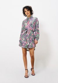 Blumenmuster-Kleid mit langen Ärmeln, einem Kragen und einer taillierten Taille. Hat lebendige Farben: grün, pink und lila. Glatte Stoffqualität.