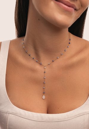 Collar de cadena de oro que presenta cuentas azules variadas y un colgante central. Las cuentas son redondas y facetadas, dispuestas en un patrón delicado.