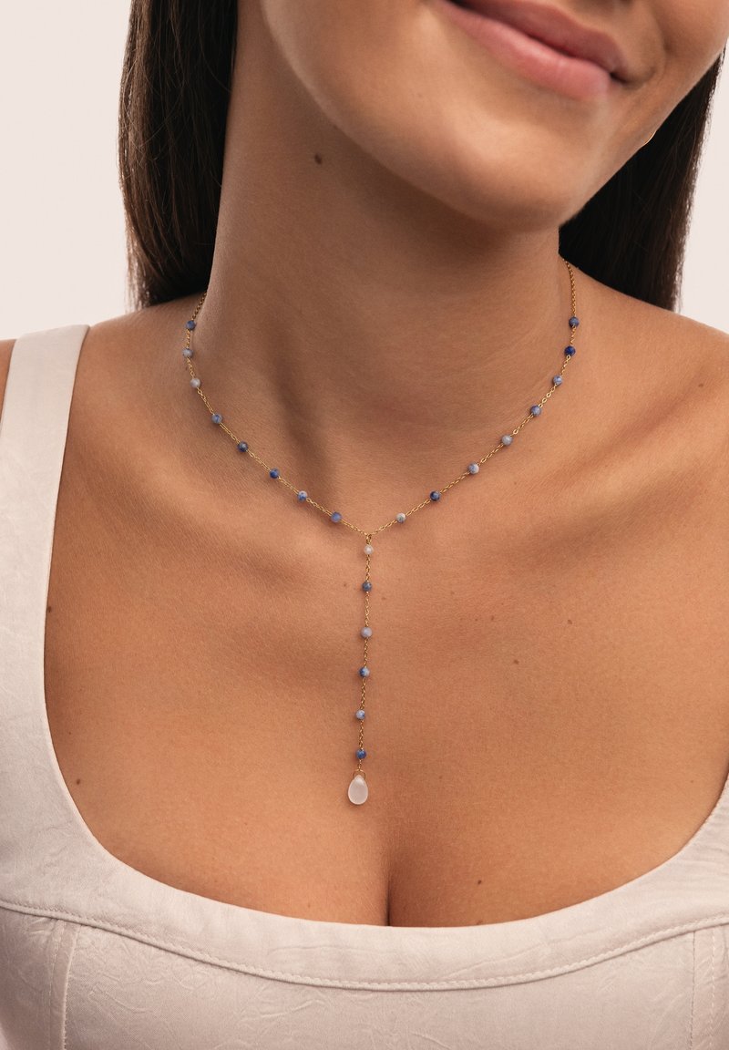 Collar de cadena de oro que presenta cuentas azules variadas y un colgante central. Las cuentas son redondas y facetadas, dispuestas en un patrón delicado.