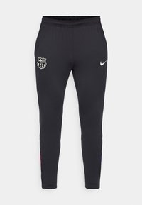 Czarne spodnie sportowe o dopasowanym kroju, z logo Nike w kolorze srebrnym oraz emblematem FC Barcelony. Materiał wydaje się gładki, z elastycznym pasem.