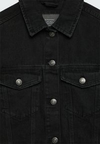 Černá džínová bunda se zapínáním na knoflíky, dvěma náprsními kapsami a stříbrnými detaily. Tkanina má hladký, mírně strukturovaný povrch.