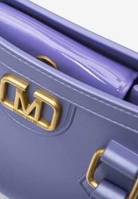 Borsa a tracolla sintetica viola con logo in tono oro, texture liscia e dettagli con doppio manico. L'interno presenta un dettaglio lucido color lavanda.