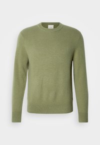 Világoszöld pulóver hosszú ujjal, kerek nyakkivágással, bordázott mandzsettával és szegéllyel. Puha tapintású anyagból készült. Nem láthatók minták vagy díszítések.