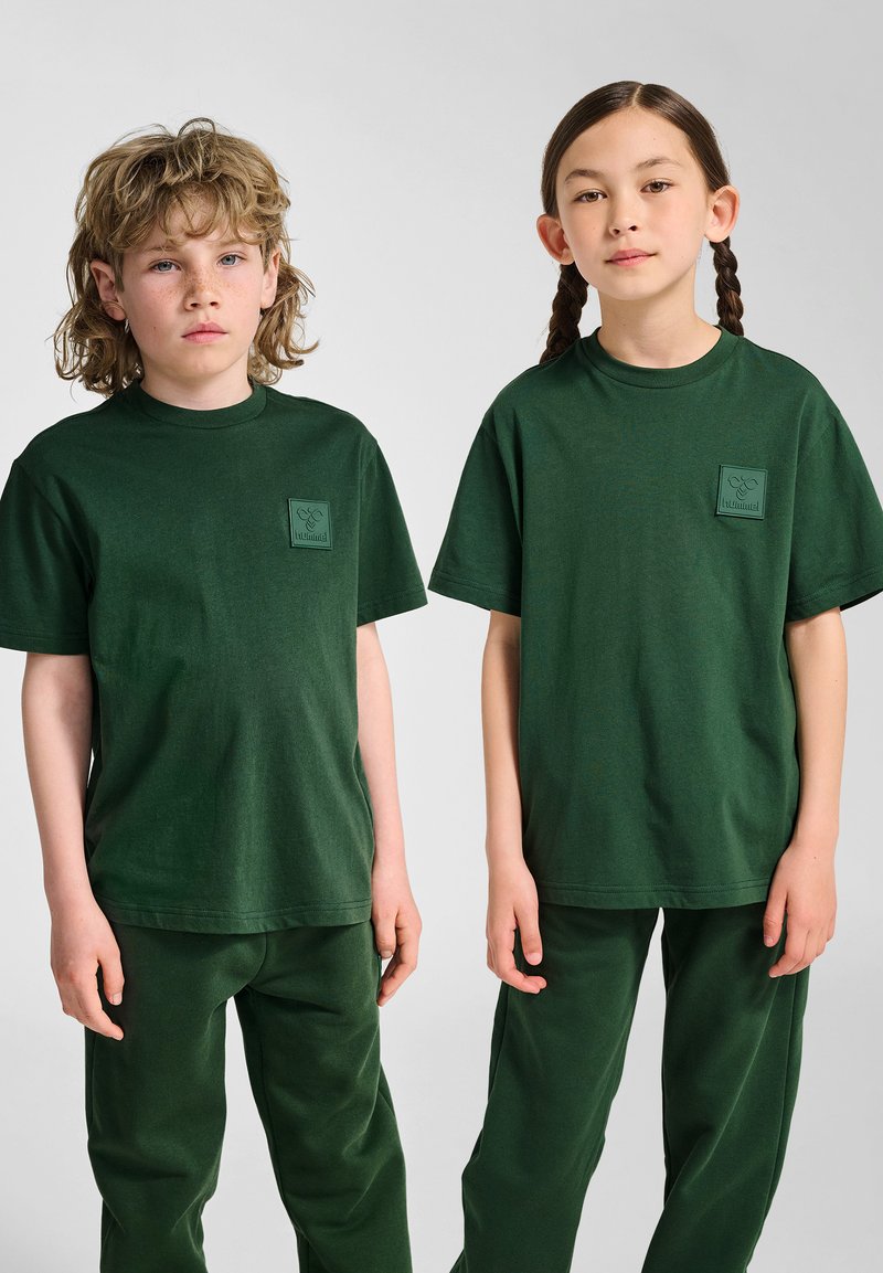 Grønne bomulds t-shirts med korte ærmer og lomme, parret med matchende grønne bukser. Enkle, afslappede pasform og glat tekstur.