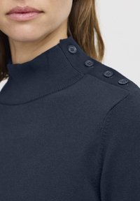 Maglione a collo alto di colore blu navy, con una texture liscia e morbida, caratterizzato da un alto colletto e quattro bottoni sulla spalla.