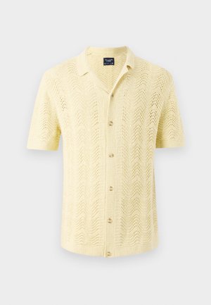 Košulja kratkih rukava od svijetložutog pletenog materijala s valovitim uzorkom i zatvaranjem na dugmad, s ovratnikom i opuštenim krojem.