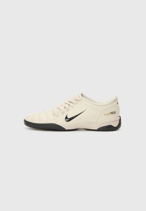 Chaussure de football Nike Total 90 III blanche avec semelle noire et logo swoosh noir, vue de profil sur un fond uni.