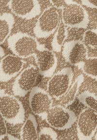 Pletiva od vune sa bež i krem uzorkom leopardskog printa te metalnim nitima, stvarajući teksturiran i moderan izgled.