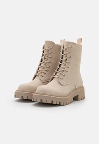 Beige snørebånd ankle boots lavet af blødt suede, med en kraftig gummisål og en træksløjfe bagpå for nem påtagning.