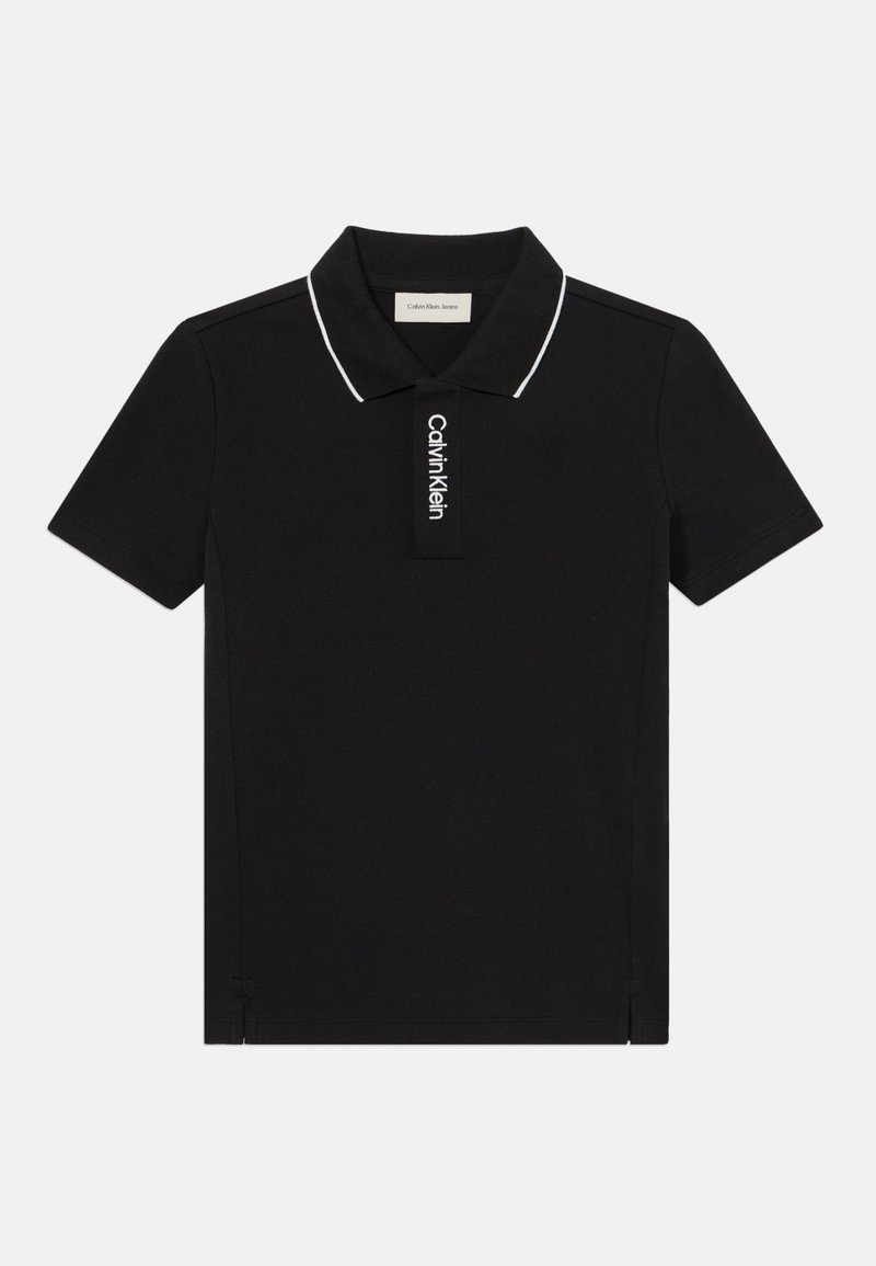 Svart polo-skjorte laget av bomull med hvit krage og sømmer. Har en vertikal Calvin Klein-logo på knappestolpen. Korte ermer.