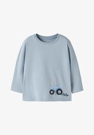 Heleroheline pika varrukaga beebisärk, kus on väike sinine traktoripilt ja kolm musta rehvimarki alumisel äärel.