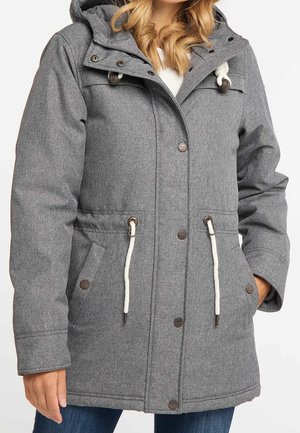 Veste d'hiver grise à capuche avec des cordons blancs, des boutons-pression à l'avant et des poches latérales portée sur un jean bleu.