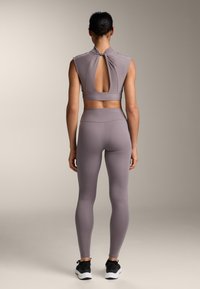 Completo sportivo in lavanda tenue, composto da un top senza maniche con una scollatura sul retro e leggings a vita alta, realizzati in tessuto elasticizzato.