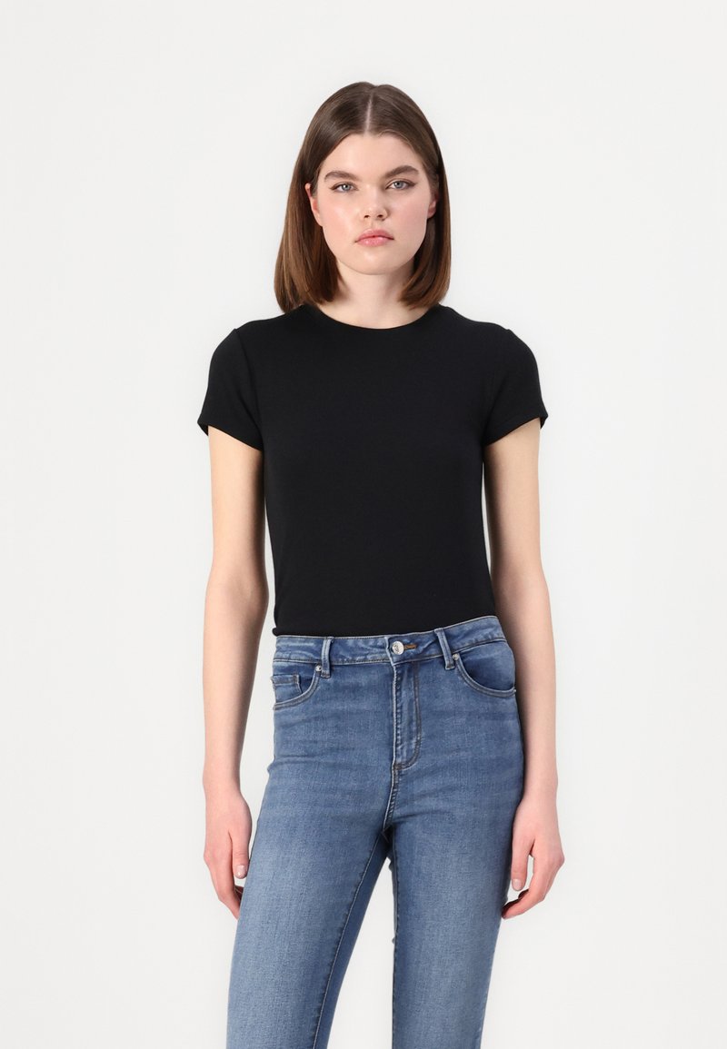 Tricou negru, cu mânecă scurtă, ajustat, dintr-un material neted, asociat cu blugi ușor albaștri, cu talie înaltă, având un design clasic cu cinci buzunare.