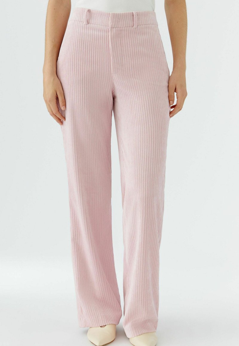 Pantalon en velours côtelé rose pâle avec texture à côtes verticales, doté d'une taille haute et d'une coupe large. Devant et ourlet lisses et sans ornements.