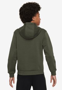 Sudadera verde oliva con capucha ajustable, puños y dobladillo de canalé, confeccionada en un material suave y texturizado, vista desde la parte posterior.