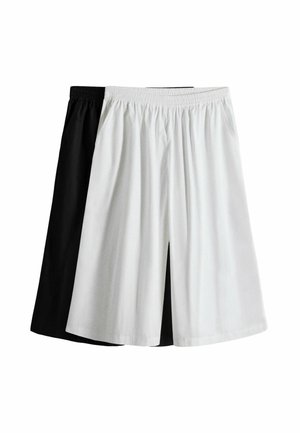 Két pár bő, térdig érő rövidnadrág elasztikus derékpánttal, az egyik fehér elöl, a másik fekete hátul, fehér háttéren.