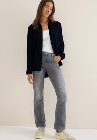 Mörk marinblå knapp-up skjorta, vit linne, ljusgrå jeans och beige sneakers. Mjuk tyg och avslappnad passform med klassisk design.
