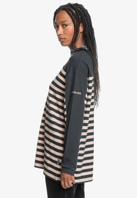Striped long-sleeve shirt featuring navy and light pink fabric, a relaxed fit, and logo detail on the sleeve.
