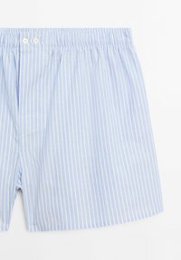 Boxers à rayures bleu clair en coton doux. Dotés d'une taille élastique avec deux boutons à l'avant et d'une coupe ample.