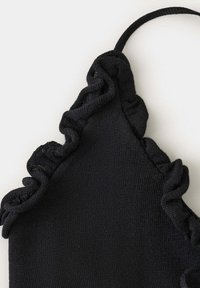 Tissu tricoté noir avec bords froncés et une fine bretelle, probablement partie d'un vêtement comme un haut ou une robe.