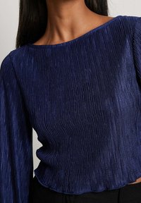 Marineblauwe geplooide top met een bootnecklijn, lange mouwen en een gestructureerde glans. Aansluitend ontwerp met een cropped zoom.