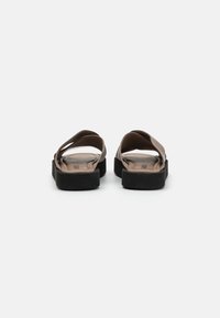 Brown sandals with a smooth, soft upper and thick black rubber sole; features two wide straps crossing at the front.