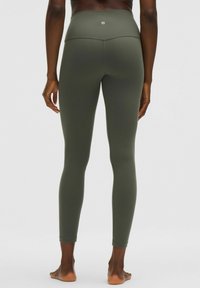 Legginsy w kolorze oliwkowym z wysokim stanem, wykonane z gładkiego, elastycznego materiału, z bezszwowym wykończeniem i bez wyraźnego logo z tyłu.