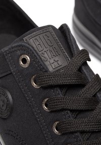 Musthave mustvalged mustre raamatud mustvalged sneakerid, millel on tekstuuriga pind, ümmargused paelad, metallist silmadega ja tõstetud kummist logo silt keeles.