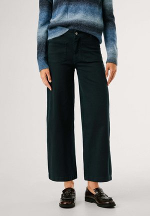 Donkergroene wijde broek met twee voorzakken en een knoopsluiting, gecombineerd met een gradient blauwe gebreide trui en zwarte loafers.