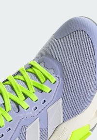 Light grey athletic shoe featuring mesh upper, neon green laces, adjustable lacing system, and contrasting textured sole with accent details.