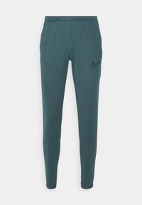 Teal slim-fit Nike trainingsbroek met een elastische tailleband en zwart swoosh logo op de bovenste linker dij, tegen een witte achtergrond.