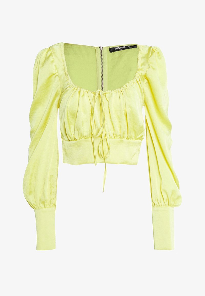 Blouse courte jaune clair avec manches longues bouffantes, encolure carrée, détail noué à l'avant et fermeture éclair dans le dos.