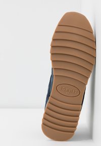 Semelle d'une chaussure Esprit bleue avec une semelle extérieure en caoutchouc brun rainurée, taille 37, positionnée verticalement sur un fond blanc.