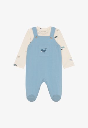 Niebieskie bawełniane ogrodniczki z paskami na guziki i przednią kieszenią z motywem wieloryba. Pod spodem kremowa koszula z długim rękawem ozdobiona małymi wzorami rybek.