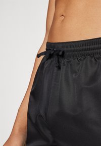 Sorte, lette shorts med elastisk midjebånd og justerbar snor; glatt tekstur med en avslappet passform.