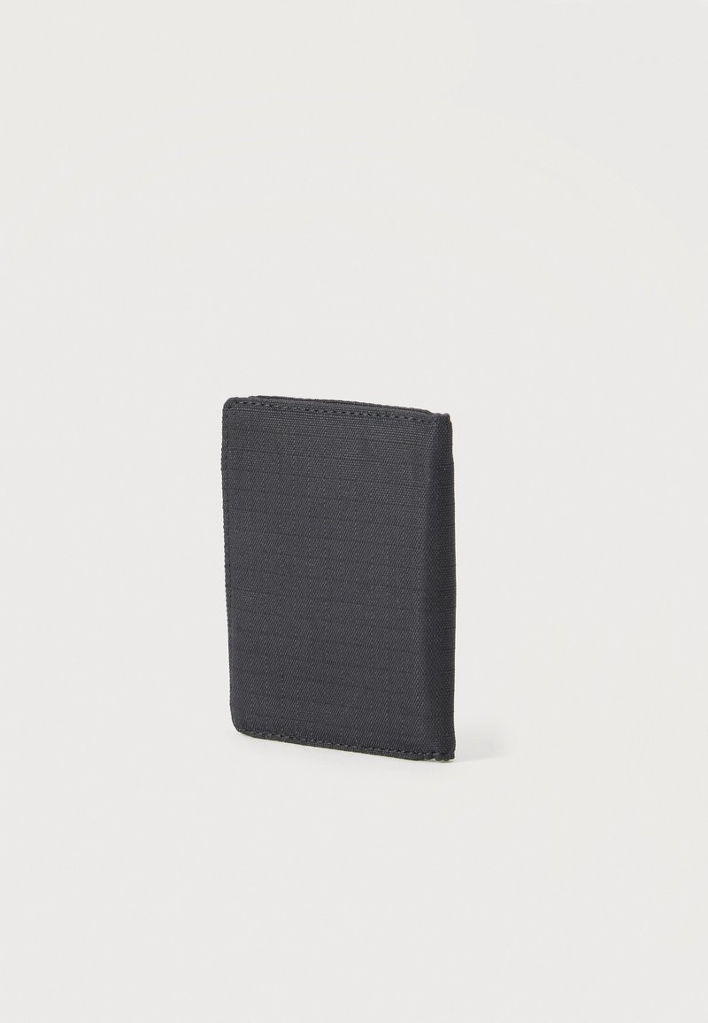 Portefeuille en tissu noir debout sur un fond blanc, présentant un design plié et minimaliste avec des coutures visibles.