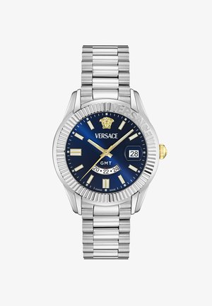 Hodinky Versace GMT s modrým ciferníkom, strieborným nerezovým remienkom, žltými akcentmi, displejom dátumu a gravírovaným lunetom.