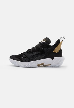 Schwarzer und goldener Basketball-Sportschuh mit weißer Sohle, Mesh-Obermaterial, Schnürsenkeln und Zuglasche auf neutralem Hintergrund.