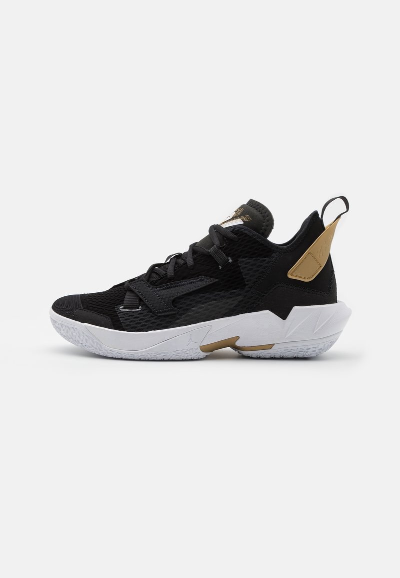 Chaussure de basketball athlétique noire et dorée avec semelle blanche, dessus en mesh, lacets et languette sur fond neutre.