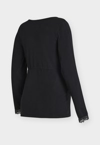 Czarna bluzka z długim rękawem wykonana z miękkiego materiału, z okrągłym dekoltem i koronkową lamówką na końcach rękawów. Dopasowany fason w talii.