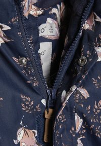 Navy zippered jacket featuring a floral pattern in light colors, textured fabric, and a snap closure near the collar. Size tag visible.