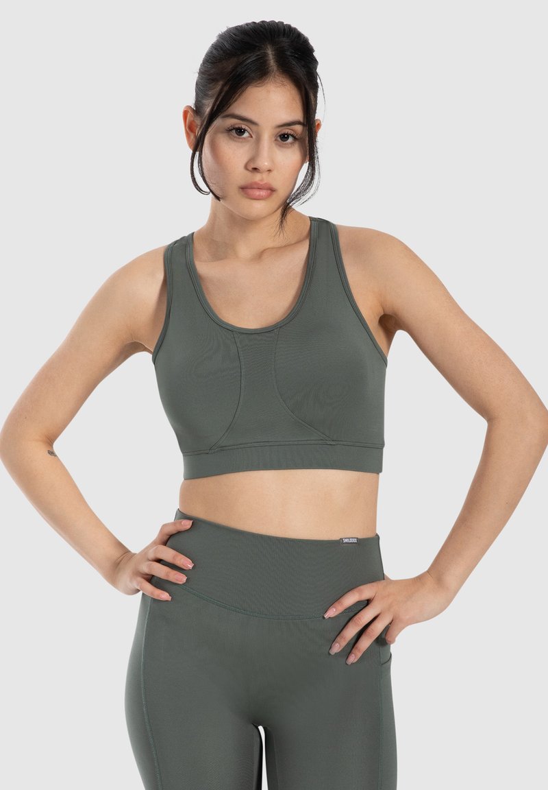 Sujetador deportivo de color verde oliva con un diseño ajustado, tirantes anchos y tela texturizada. Costuras en el busto y una banda elástica en el dobladillo.