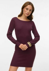 Rievota vīna sarkana adīta kleita ar garām piedurknēm un laivas formālu kakla izgriezumu. Izceļas ar pieguļošu siluetu un teksturētu audumu. Vienkāršs dizains zem ceļa.