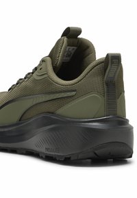 Scarpa da ginnastica verde oliva con tomaia in rete texturizzata, dettagli neri e suola nera spessa e imbottita. Presenta una piccola linguetta sul tallone.