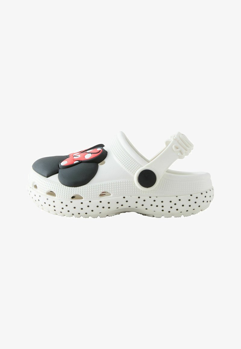 Zapato estilo zueco blanco con suela negra con lunares y decoración en la parte superior con orejas y lazo de Minnie Mouse en rojo y negro.