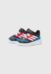 Sneaker neri con motivo a ragnatela, accenti rossi e blu, strisce bianche e una fascia in velcro. Suola in gomma con grip testurizzato.