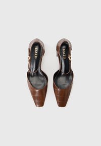 Ruskea tekonahkainen slingback-kengät, joissa on kärkiosa, crocodile-tekstuurilla ja kultaisilla yksityiskohdilla. Logo näkyvissä sisäpohjassa.